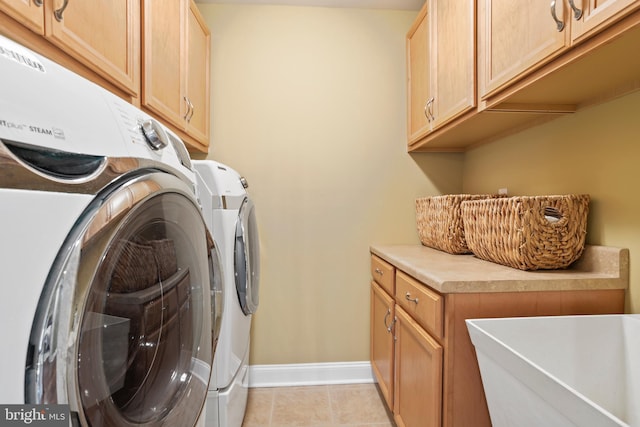 washroom with washing machine and dryer, cabinet space, a sink, baseboards, and light tile patterned flooring
