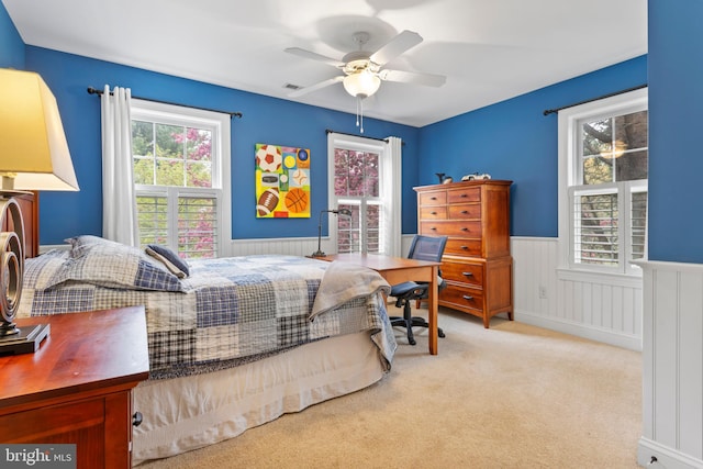 bedroom with multiple windows, carpet, wainscoting, and ceiling fan