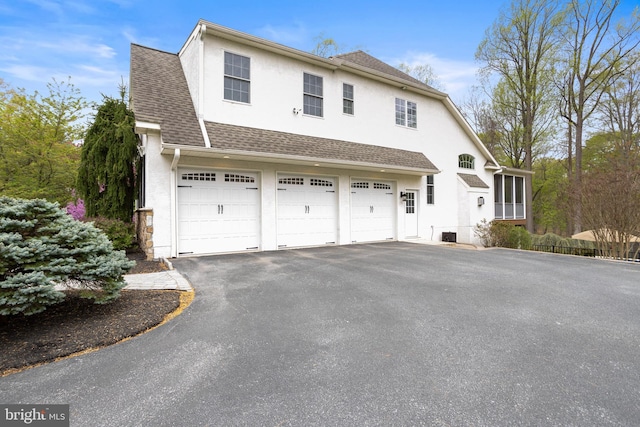 view of home's exterior featuring roof with shingles, an attached garage, driveway, and stucco siding