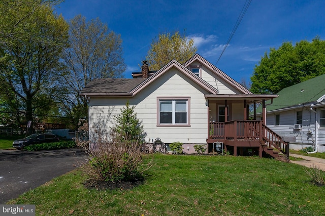 bungalow-style home with a front lawn, a chimney, and covered porch