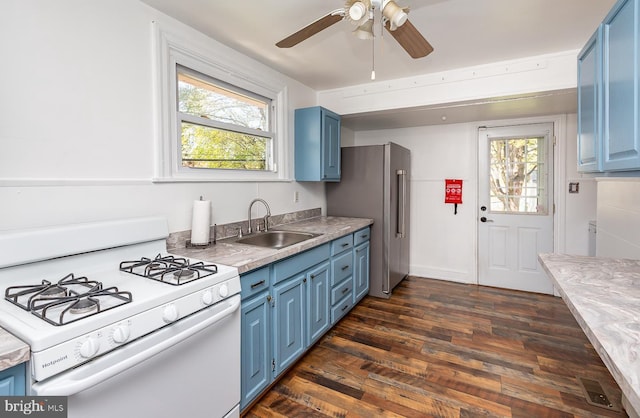 kitchen featuring white gas stove, a healthy amount of sunlight, blue cabinetry, and a sink