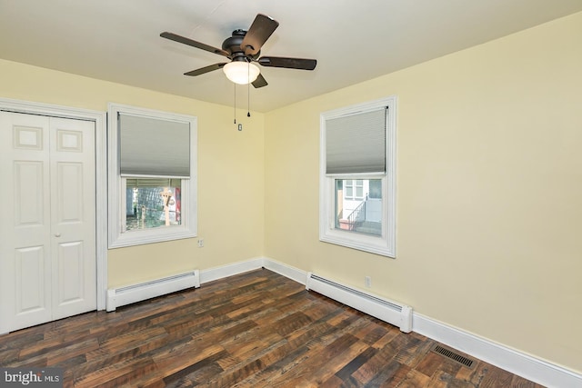 unfurnished bedroom with baseboard heating, dark wood finished floors, visible vents, and a closet