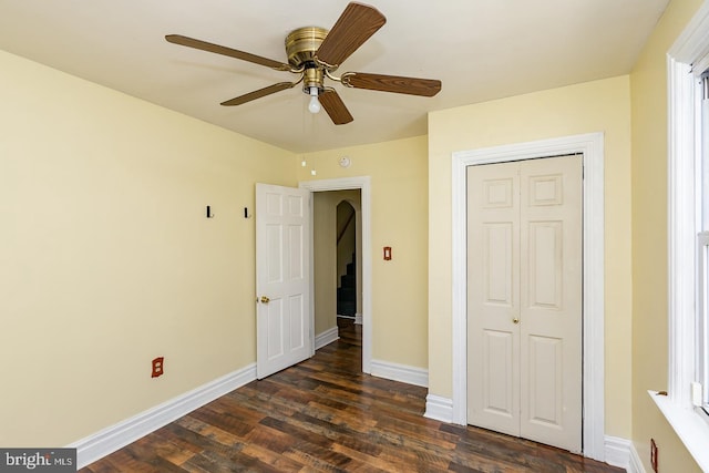 unfurnished bedroom featuring baseboards, a closet, a ceiling fan, and dark wood-style floors