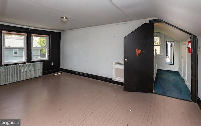 spare room with hardwood / wood-style flooring, radiator, lofted ceiling, and a healthy amount of sunlight
