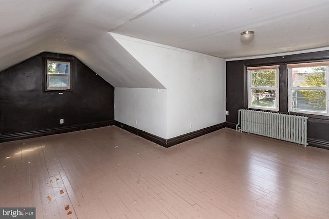 additional living space featuring baseboards, radiator heating unit, lofted ceiling, and hardwood / wood-style flooring