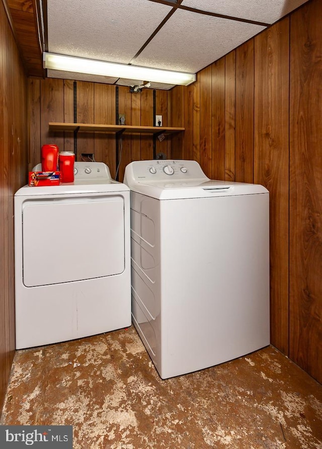 clothes washing area featuring separate washer and dryer, wooden walls, and laundry area