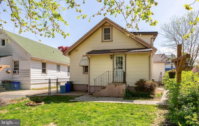 rear view of house with a gate, a yard, and fence