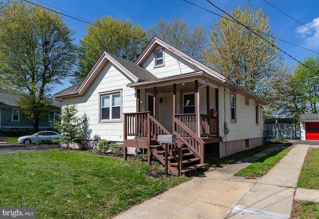 bungalow featuring driveway, a front lawn, and covered porch