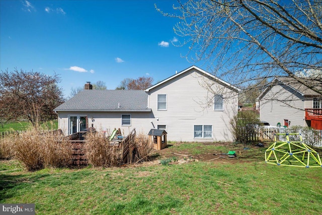rear view of property with a lawn, fence, and a chimney