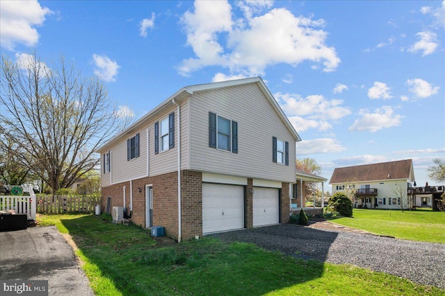 view of side of home featuring brick siding, a garage, a yard, and driveway