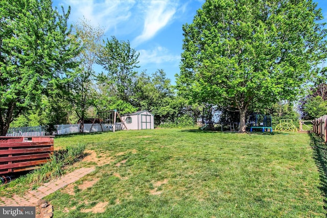 view of yard featuring a fenced backyard, a trampoline, an outbuilding, and a storage shed