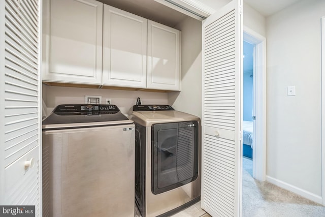 laundry area featuring cabinet space, separate washer and dryer, baseboards, and light colored carpet