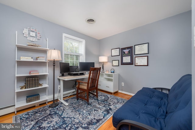 office with baseboards, wood finished floors, visible vents, and baseboard heating