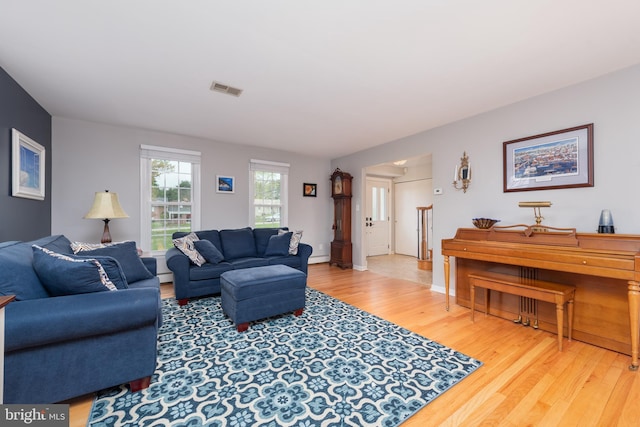 living area featuring a baseboard heating unit, baseboards, wood finished floors, and visible vents