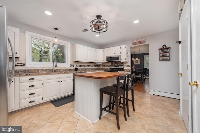 kitchen with stainless steel appliances, a sink, a baseboard heating unit, butcher block counters, and decorative backsplash