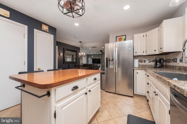 kitchen with stainless steel appliances, a sink, an inviting chandelier, and butcher block countertops