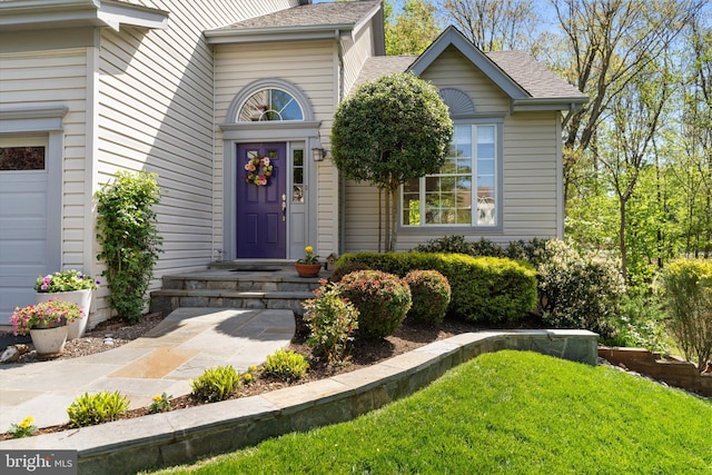 property entrance with roof with shingles and a yard