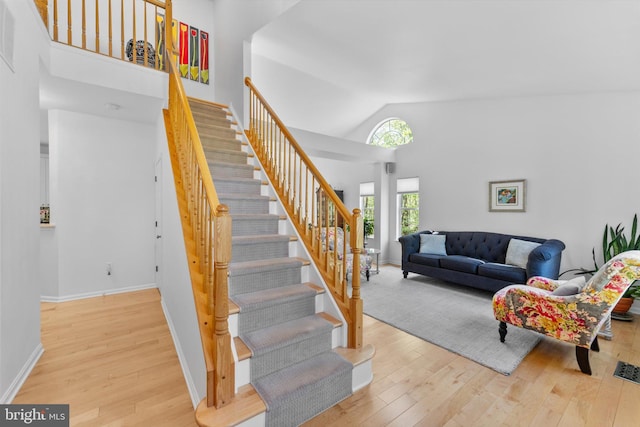 stairs featuring high vaulted ceiling, baseboards, hardwood / wood-style floors, and visible vents