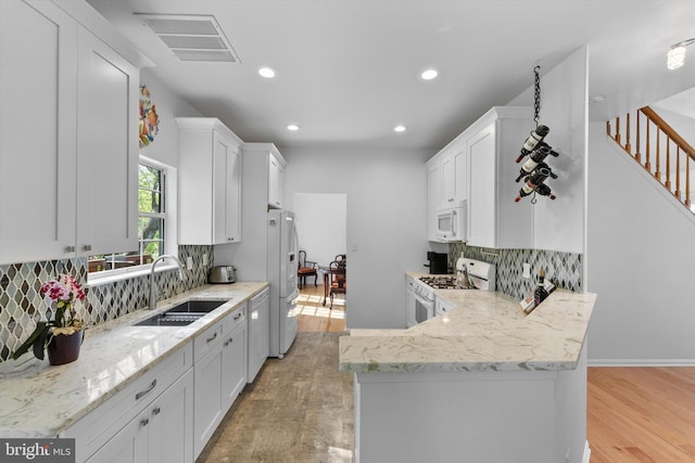 kitchen featuring visible vents, tasteful backsplash, a sink, white appliances, and white cabinetry