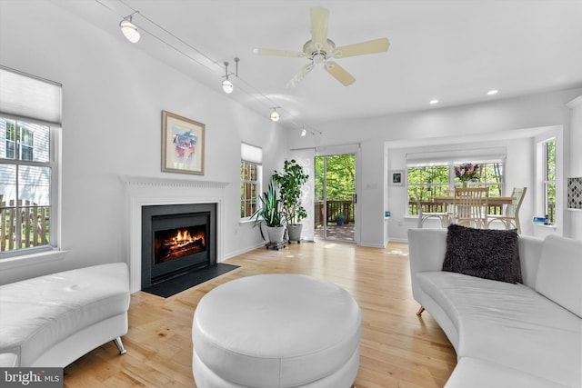 living room with track lighting, ceiling fan, light wood-type flooring, recessed lighting, and a fireplace with flush hearth