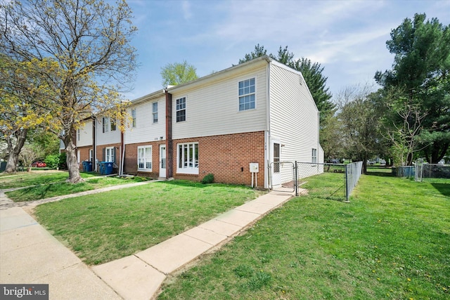 view of front of house with fence, a front yard, a gate, and brick siding
