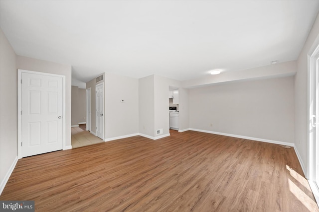 unfurnished living room featuring baseboards, visible vents, and light wood-style flooring