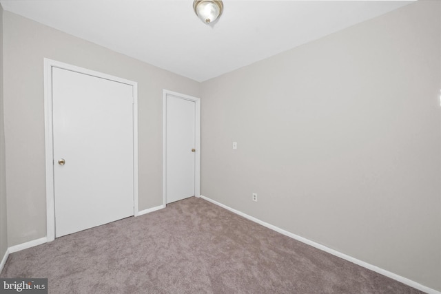 unfurnished bedroom with a closet, carpet flooring, and baseboards