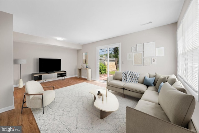 living area with wood finished floors, visible vents, and baseboards