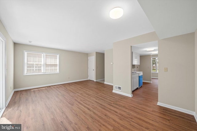 unfurnished living room featuring baseboards, wood finished floors, and visible vents