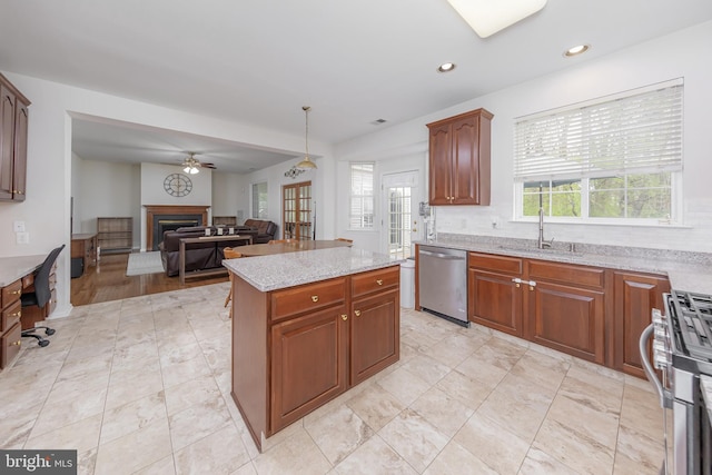 kitchen featuring a fireplace, open floor plan, ceiling fan, a sink, and appliances with stainless steel finishes
