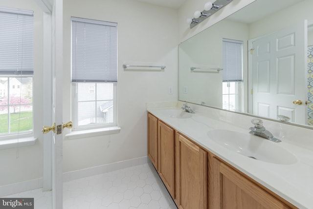 full bathroom with double vanity, a sink, baseboards, and tile patterned floors