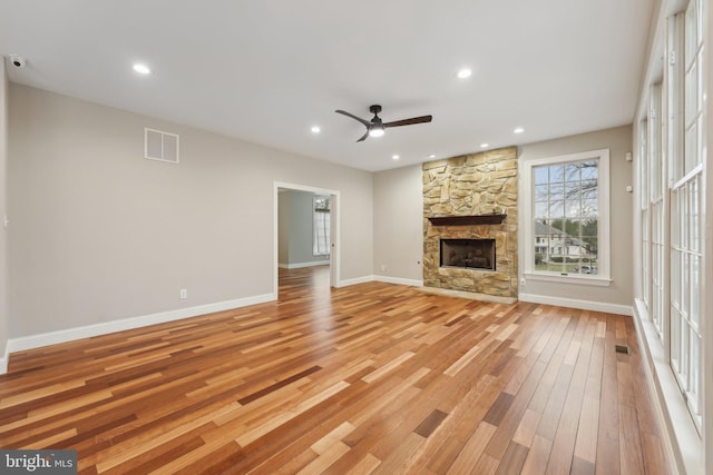 unfurnished living room featuring light wood finished floors, visible vents, a ceiling fan, baseboards, and a fireplace