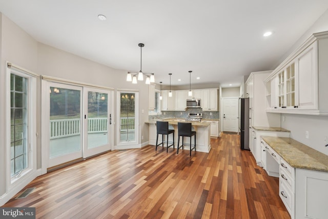 kitchen featuring a wealth of natural light, appliances with stainless steel finishes, a kitchen breakfast bar, and wood finished floors