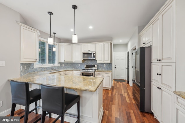 kitchen with backsplash, wood finished floors, stainless steel appliances, and a breakfast bar