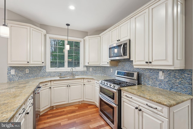 kitchen with light wood-type flooring, decorative backsplash, stainless steel appliances, and a sink