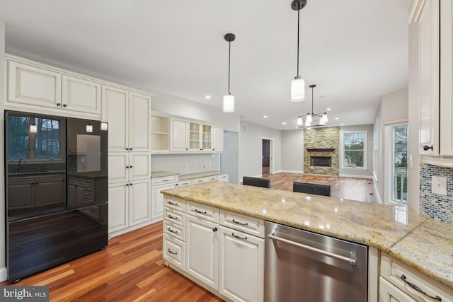 kitchen with light wood-type flooring, dishwasher, freestanding refrigerator, and a fireplace