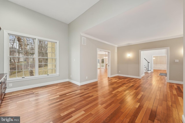 unfurnished living room featuring stairway, visible vents, light wood-style floors, crown molding, and baseboards