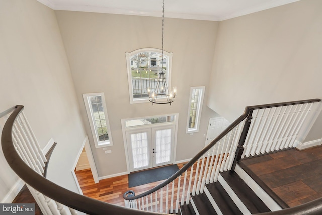 foyer entrance with baseboards, a high ceiling, a chandelier, and plenty of natural light