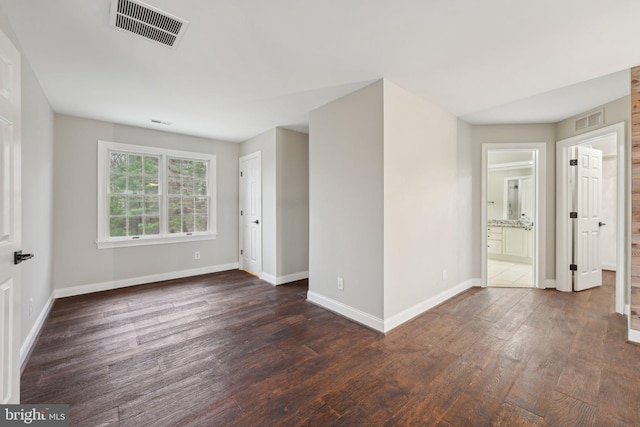 empty room with baseboards, wood finished floors, and visible vents