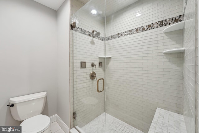 bathroom featuring a shower stall, toilet, and baseboards