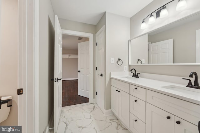 bathroom with marble finish floor, baseboards, a sink, and double vanity