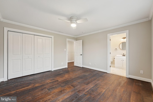 unfurnished bedroom featuring dark wood-style floors, baseboards, a ceiling fan, a closet, and crown molding