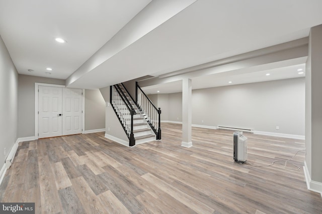 finished below grade area with stairway, baseboards, and a baseboard radiator