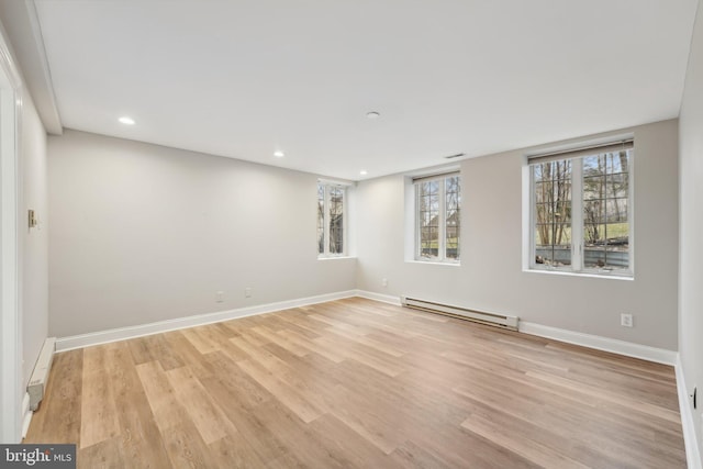empty room with a baseboard heating unit, baseboards, recessed lighting, and light wood-style floors
