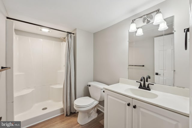 full bath with a shower stall, toilet, vanity, and wood finished floors