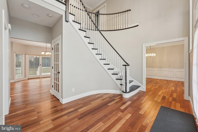 foyer with hardwood / wood-style flooring, a high ceiling, a notable chandelier, and stairway
