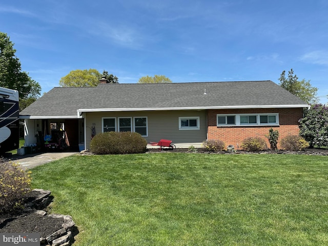 view of front of house with a chimney, a front yard, brick siding, and an attached carport