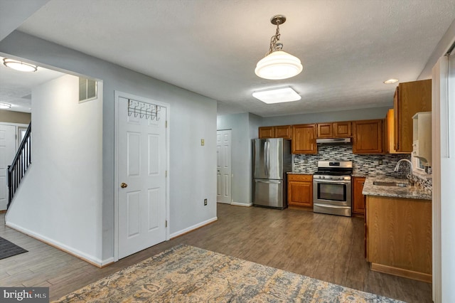 9208 Homestretch Ct, Laurel, MD 20723 - kitchen featuring brown cabinetry, appliances with stainless steel finishes, a sink, under cabinet range hood, and dark wood-type flooring