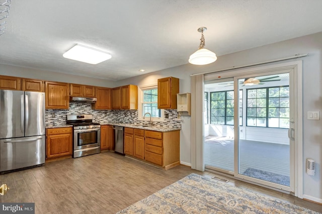 9208 Homestretch Ct, Laurel, MD 20723 - kitchen with brown cabinets, a sink, stainless steel appliances, tasteful backsplash, and under cabinet range hood