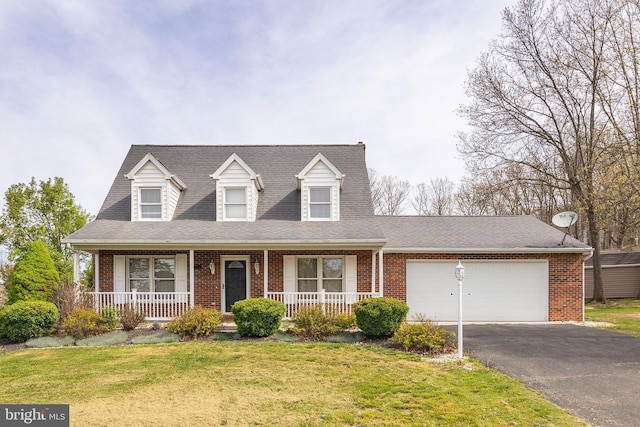 cape cod-style house featuring aphalt driveway, covered porch, a front yard, brick siding, and a garage
